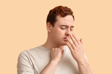 Young man with sore throat on beige background