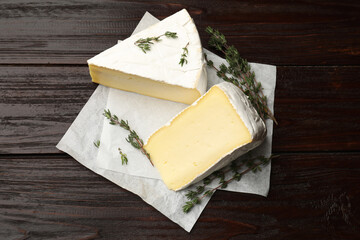 Pieces of tasty camembert cheese and thyme on wooden table, top view