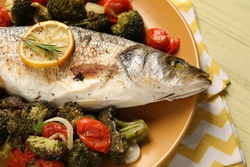 Delicious baked fish and vegetables on table, closeup