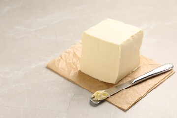 Block of tasty butter and knife on light table. Space for text