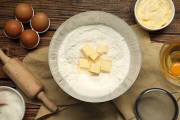 Flat lay composition with fresh butter and flour in bowl among other products on wooden table