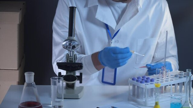 Health care worker with blood test tubes in clinical laboratory. Medical examiners hand holding blood sample for analysis in clinical research laboratory. Disease prevention starting in science center