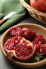Cut fresh pomegranate and green leaves on grey table, closeup