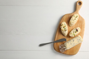 Tasty butter with green onion, olives and knife on white wooden table, top view. Space for text