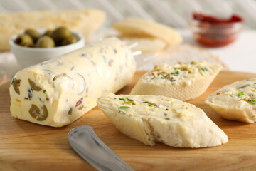 Tasty butter with olives, green onion and bread on wooden board, closeup