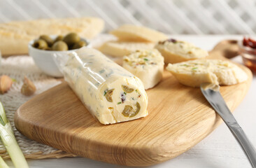 Tasty butter with olives, green onion, bread and knife on white wooden table