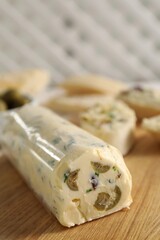 Tasty butter with olives and green onion on wooden table, closeup