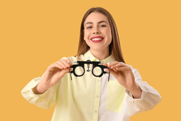 Young woman with trial frame on yellow background