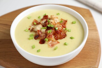 Tasty potato soup with bacon, green onion and croutons in bowl on white table, closeup