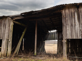 Old falling wooden barn on abandoned farm. Economy and recession effect on agriculture industry and...