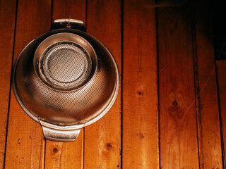Stainless steel bowl hanging on a wooden wall. Country style interior decoration of a house.
