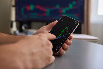 Crypto trader investor broker holding finger using cell phone app executing financial stock trade...