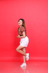 The elegance of a cheerful indonesia woman has her arms and legs crossed in front of her, wearing a brown blouse and shorts with a red background. for fashion, lifestyle and clothing concepts