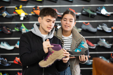 Married couple choose winter trekking shoes together in a sports shop
