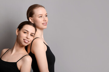 Beautiful sisters on grey background