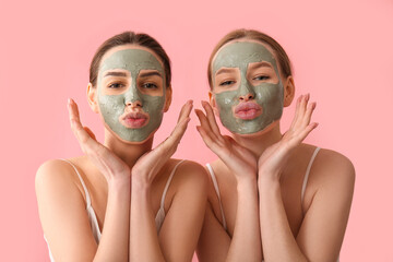 Beautiful young sisters with facial masks on pink background