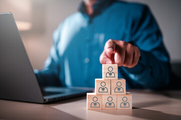 assessment, employment, hire, human, job, leader, leadership, talent, group, management. A man pointing at a stack of wooden blocks with people on them. The blocks are arranged in a pyramid shape.
