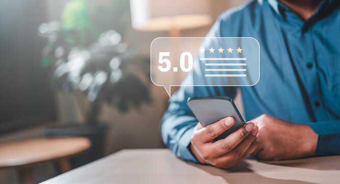 evaluation, analysis, feedback, management, satisfaction, opinion, rank, reputation, result, review. A man is holding smartphone with a 5.0 rating on it. The man is sitting with a potted plant.