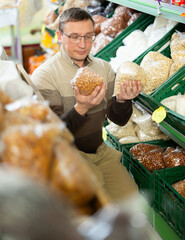 Male shopper selects various nuts in the produce section of a supermarket