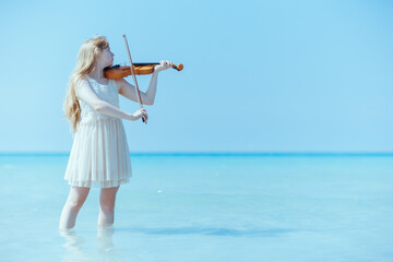 modern teenage girl in white dress enjoying playing on seashore