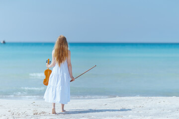 relaxed modern teenage girl in light dress on ocean shore