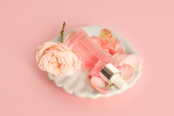 Composition with bottle of cosmetic oil, rose and petals on pink background