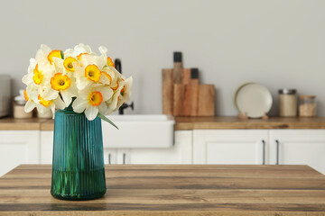 Vase with yellow flowers on table in stylish kitchen