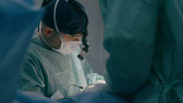 Doctor man in uniform physician surgeon medic nurse performing surgical operation at hospital clinic plastic surgery microsurgery saving life patient health emergency medical help medicine healthcare