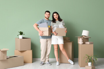 Young happy couple holding belongings in their new house