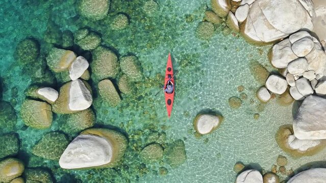 The aerial view captures a person kayaking on Lake Tahoe in California, USA. The individual paddles through the water, maneuvering the kayak along the lakes surface. 4K footage.