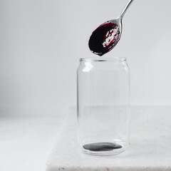 Pouring blueberry puree into can shaped glass, making aesthetic cafe drink