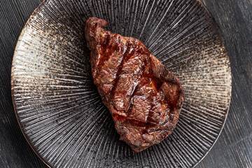 Fresh juicy delicious beef steak on a dark background. Meat dish with spices and herbs