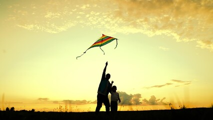 Happy family, dad with child in park playing with kite. Father, son play with kite in meadow. Dad...