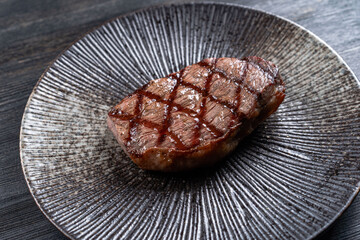 Fresh juicy delicious beef steak on a dark background. Meat dish with spices and herbs