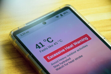 Excessive heat warning alert on mobile phone. Selective focus. Extreme weather, El Nino condition.