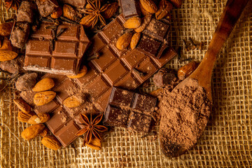 Overhead shot of chocolate pieces of different varieties with almonds and spices