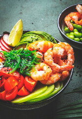 Poke bowl for balanced diet with shrimp, rice, avocado, vegetables and chuka salad, green table background, top view