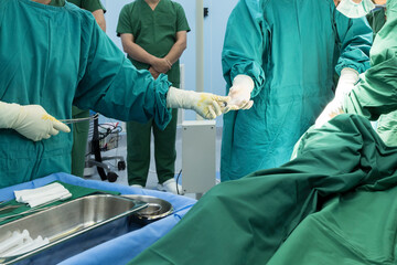 Plastic surgeon sewing up breast of female patient after inserting implants in operating...