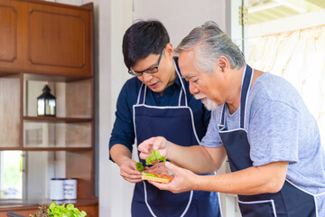 Senior Asian father and middle-aged son cooking together in kitchen, Happiness Asia family concepts