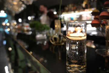 candela accesa in un bicchiere, sul bancone di un bar in una discoteca
