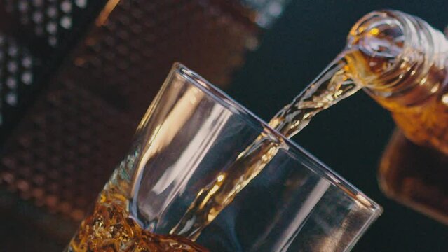 Person pouring whiskey into glass dutch angle