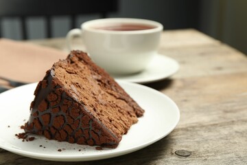 Piece of delicious chocolate truffle cake on wooden table, closeup. Space for text