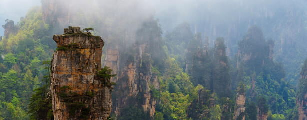 mountain landscape with fog. Towering mountain peaks atop hills in the Mount zhangjiajie surrounded...