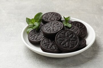 Plate with tasty sandwich cookies and mint on grey textured table, closeup