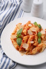 Tasty pasta with tomato sauce, cheese and basil on table