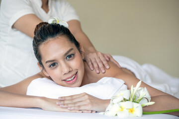 Obraz na płótnie Canvas Indulging in relaxation and wellbeing, Asian young woman with serene expression receives relaxing back massage at spa, enjoying added touch of luxury