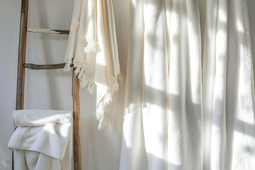 A ladder with a white towel hanging on it next to a window with a white curtain