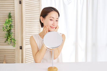 自宅でフェイシャルケアをする中年女性