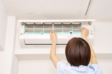 エアコンのフィルターを掃除する女性