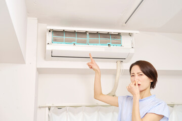 エアコンのフィルターの匂いに困る女性